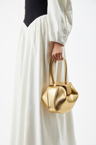 Gold Metallic Nina Bag with Model in White Dress - Lifestyle Shot | Gabriela Hearst